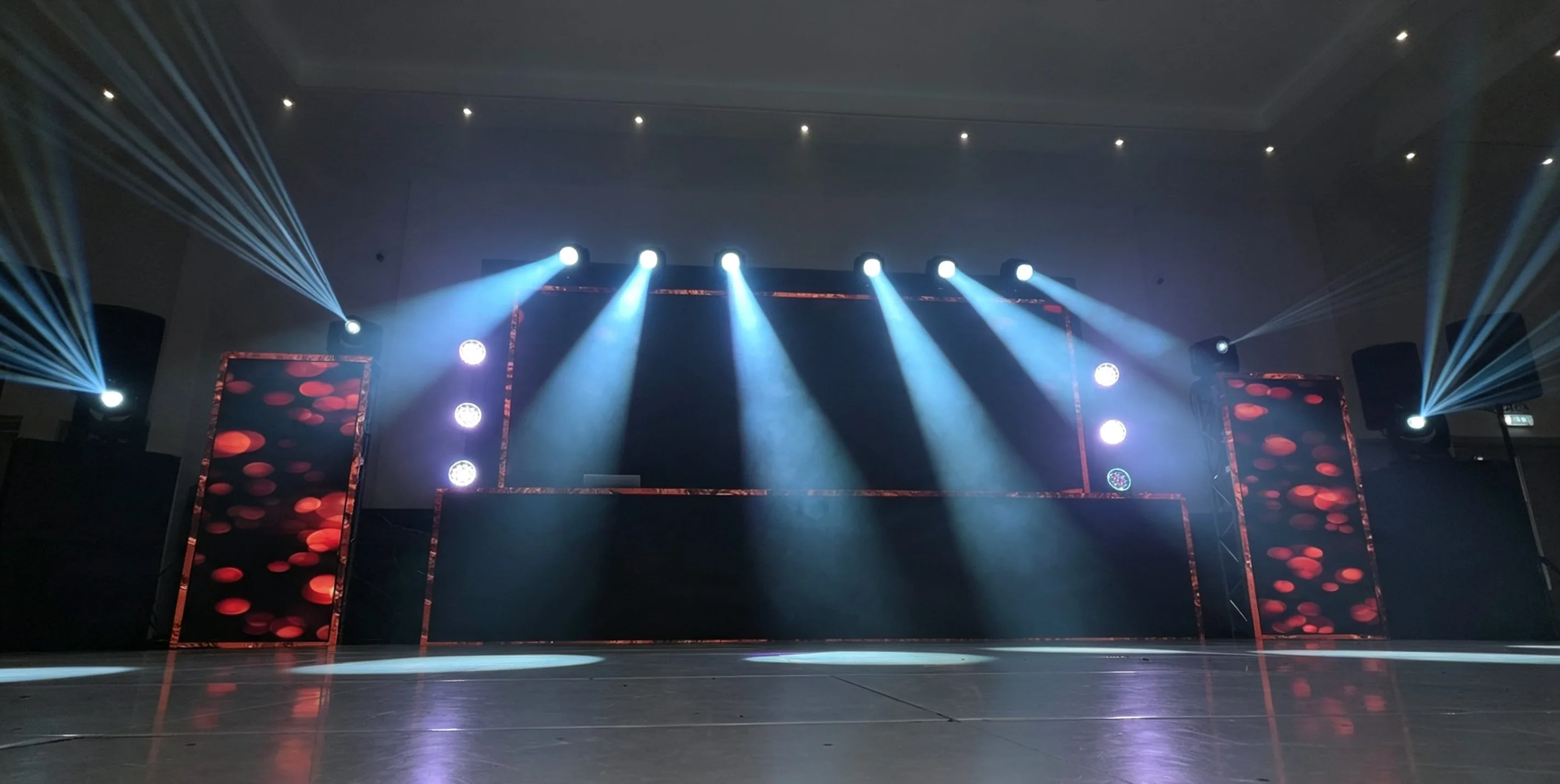 Architectural wedding lighting framing a stage and dance floor